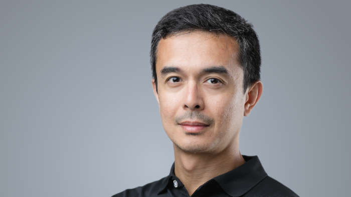 Ryan Flores blickt in einem Porträtfoto freundlich in die Kamera.