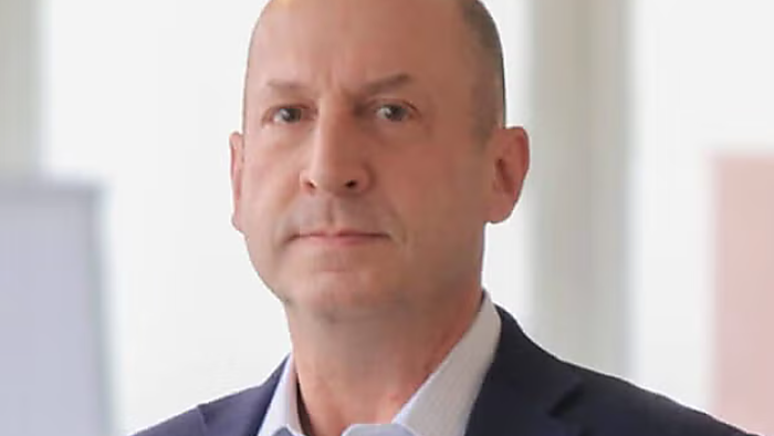 Mittelalter Herr ohne Kopfhaar, trägt einen dunkelblauen Anzug.