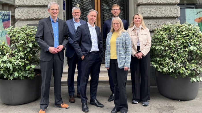 Gruppenfoto von Vereinsmitgliedern vor einer baulichen Struktur, links und rechts Bepflanzung.